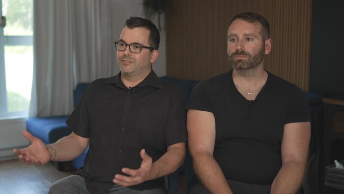 Deux hommes sont assis côte à côte.