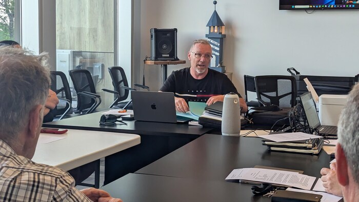 Luc Lafontaine parle à une personne autour de la table.