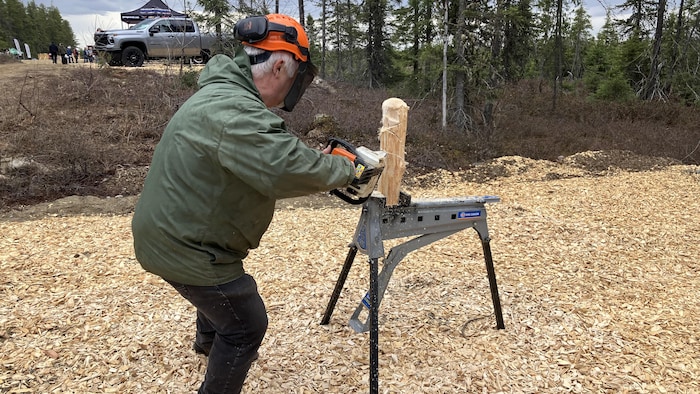 Luc Lessard en train de sculpter un morceau de bois avec sa scie à chaîne.