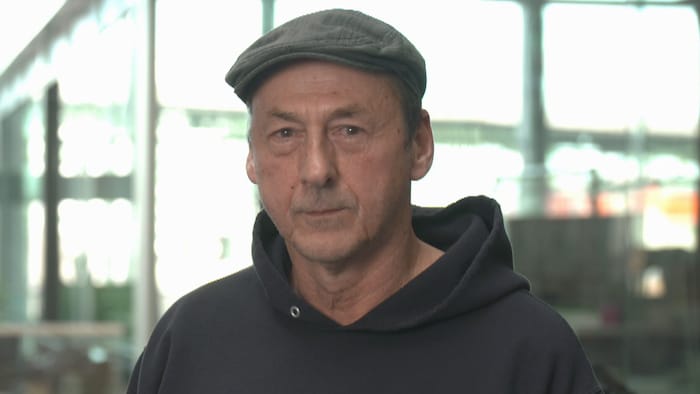 Portrait de l'acteur devant des baies vitrées.