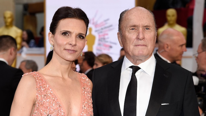 La femme et l'homme posent sur le tapis rouge.
