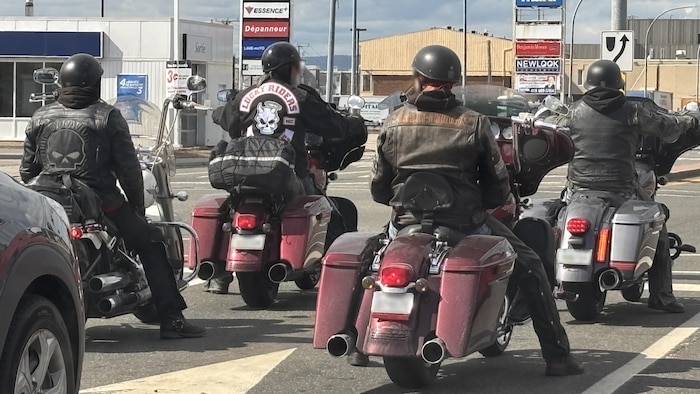 Un groupe de motocyclistes, dont un individu arborant les couleurs du groupe Lucky Riders.