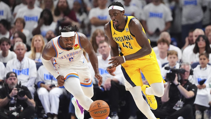 Deux basketteurs courent après le ballon.