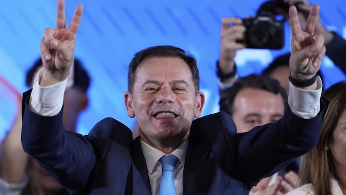 Dans une foule, Luis Montenegro a les deux mains levées.