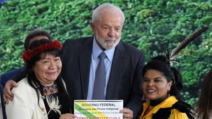 Luiz Inacio Lula da Silva se tient aux côtés de Joenia Wapichana et de Sonia Guajajara en tenant une feuille dans ses mains.