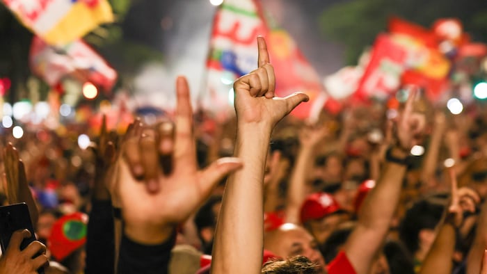 Des supporteurs de Lula font le geste « L » avec leur main en l'honneur du président.