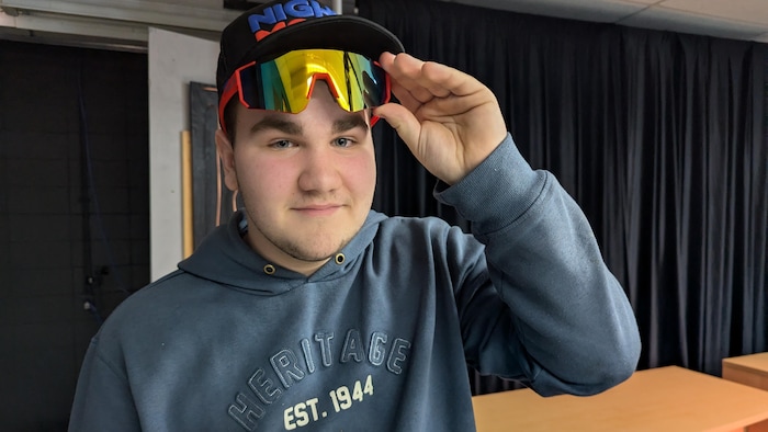 Caleb Gélinas lève ses lunettes de soleil pour montrer ses yeux.