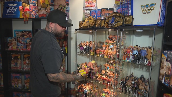 Travis Beaudry tient la figurine d'un lutteur dans sa pièce réservée à sa collection.
