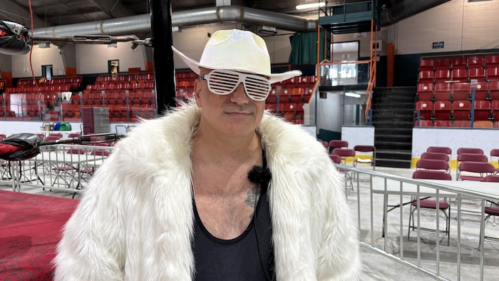 Steeve Ace porte des lunettes de soleil, un manteau de fourrure et un chapeau de cowboy.