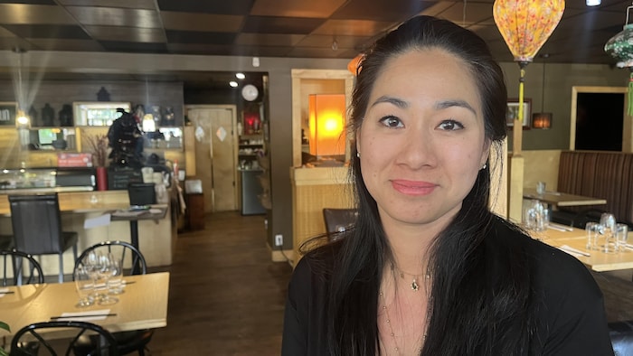 Une femme regarde la caméra dans un restaurant