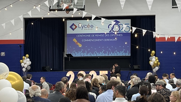 Un écran géant sur lequel il est écrit « cérémonie de remise des diplômes ».