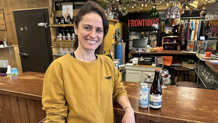 Lydia Martin-Bérubé, Frontibus is the owner of Microbrewery, in its trade counter. With a can and a bottle of beer.