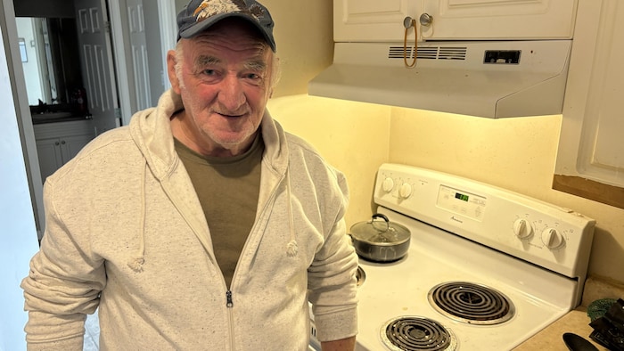 Un homme photographié dans la cuisine de son appartement, devant son four.