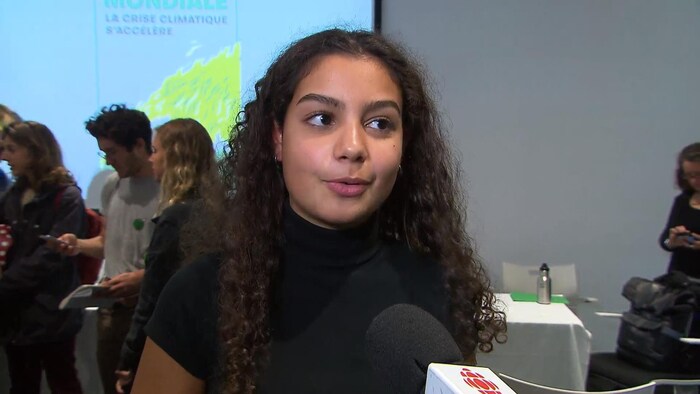 Une jeune femme en gros plan, dans une salle.