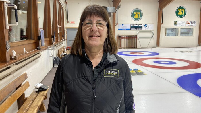 Lyne Caron est debout dans une salle de curling et se fait prendre en photo.