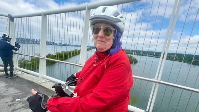 Une femme sur un vélo, sur un pont.