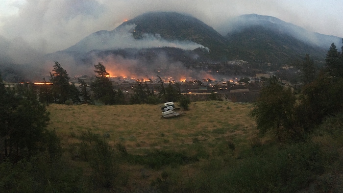 Une vue du village en flammes avec de la fumée qui s'envole.