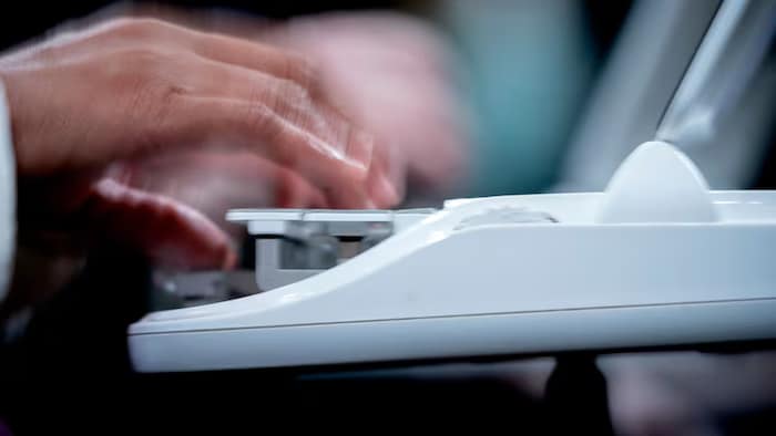 Une personne a les doigts sur une machine à transcrire des informations.