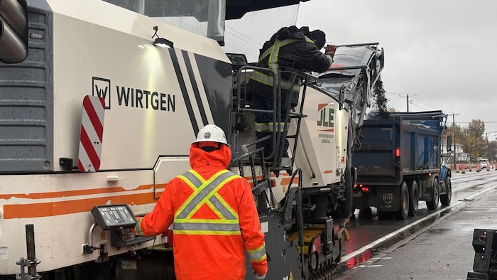 Deux travailleurs à l'oeuvre sur la machinerie pendant les travaux de pavage.