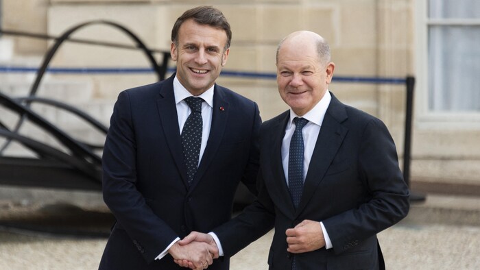 Le président français Emmanuel Macron et le chancelier allemand Olaf Scholz se donnent la main.