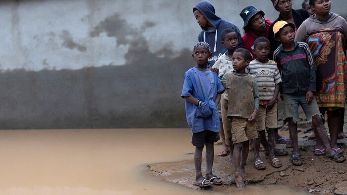 Enfants et familles près d'une zone inondée.