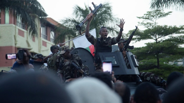 Un officier militaire malgache armé fait un geste à l'intention des manifestants.