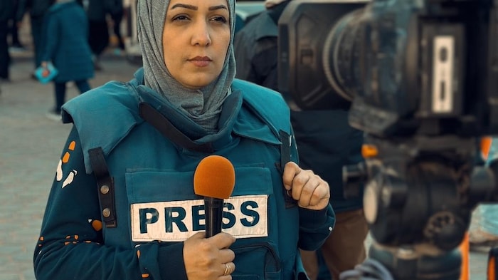 Une femme portant un gilet pare-balles sur lequel est inscrit le mot « press ».