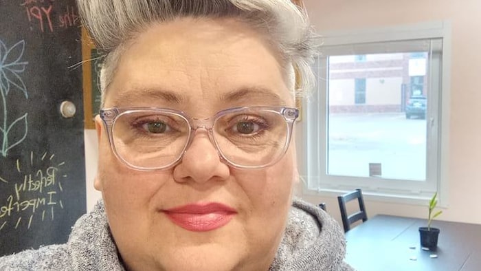 Madonna Doucette est souriante, debout dans une salle.