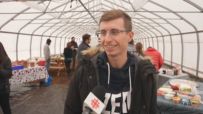 Maël Bertholom en entrevue à Radio-Canada, à l'extérieur, sous un abri temporaire.