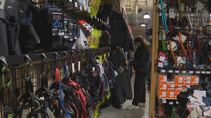 Une femme au milieu d'équipements pour les activités d'escalade, dans un magasin de Squamish, en Colombie-Britannique, mars 2026.