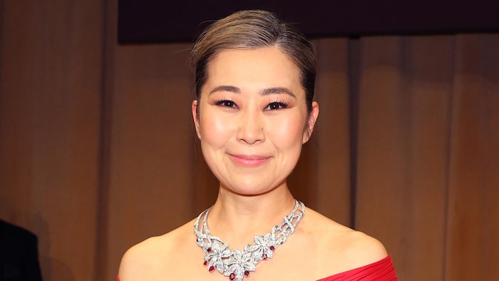 Une femme vêtue d'une longue robe rouge tient un Oscar. 