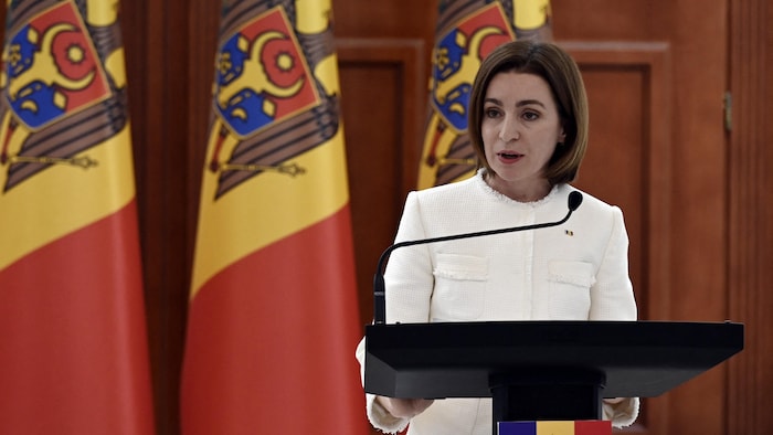 Maïa Sandu, présidente moldave au micro durant une conférence de presse devant des drapeaux de la Moldavie. 