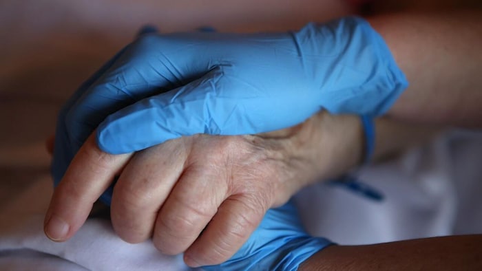 Une infirmière tient la main d'un patient.