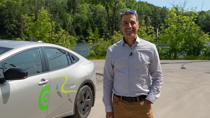 Portrait de Pierre Guénard devant une voiture en autopartage et la rivière Gatineau.