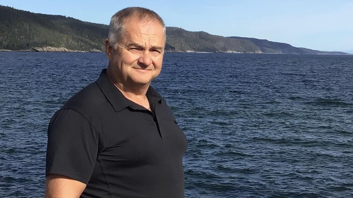 Guy Côté sourit dos au fleuve.