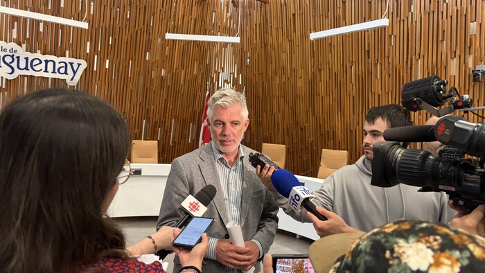 Des journalistes sont autour de Luc Boivin.
