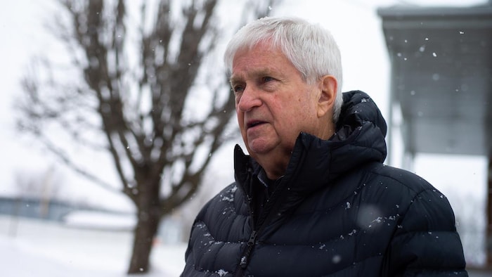 Gérard Bruneau debout, sur un trottoir durant l'hiver.