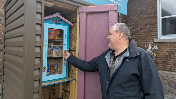 Alain Gauthier montre comment ouvrir la porte du frigo communautaire.