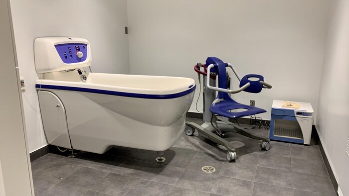 Une salle d'hydrothérapie comportant un bain et un lève-personne.