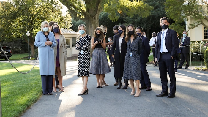 Une dizaine de personnes rassemblées à l'extérieur de la Maison-Blanche portent un masque.