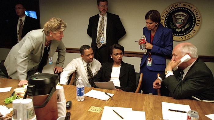 On voit les officiels assis à une table, se regardant dans les yeux, le respect  inquiet. Mme Rice, vue de face, tient des documents dans ses mains et interroge du respect  M. Cheney, qui est de profil et tient un combiné téléphonique dans sa main. D'autres hauts responsables les entourent.