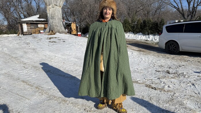 Michelle Gervais habillée en capot vert, manteau traditionnel autochtone. 