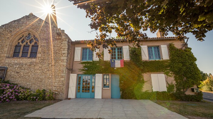 L'entrée principale du bâtiment avec un drapeau de l'Acadie au-dessus de la porte.