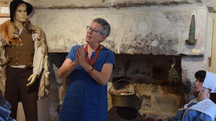 Une personne parle, et derrière elle se trouvent des pantins qui représentent une scène d'autrefois dans un musée.