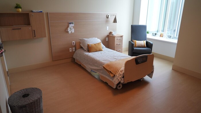 Chambre avec un lit simple, une table de chevet et un fauteuil.  