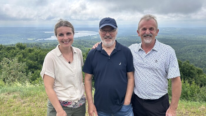Trois personnes regroupées sur le sommet d'une montagne.