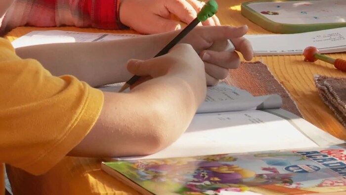La main d'un enfant en train d'écrire dans un cahier d'école 