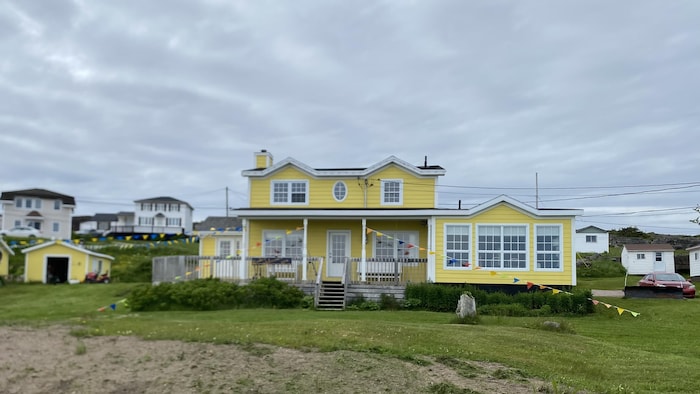 Grande maison jaune à deux étages décorée de guirlandes de fanions multicolores.