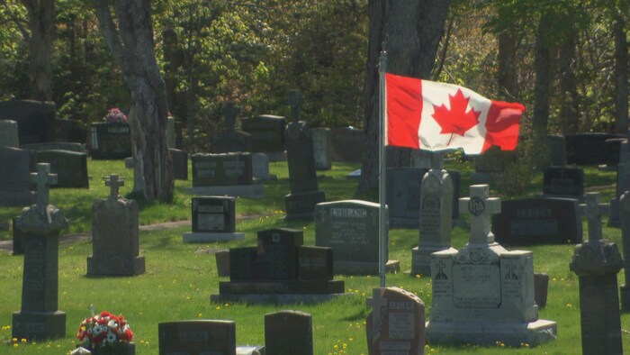 Un drapeau canadien entouré de pierres tombales. 