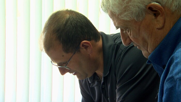 Léonce Dupuis et son fils Serge regardent des documents. 